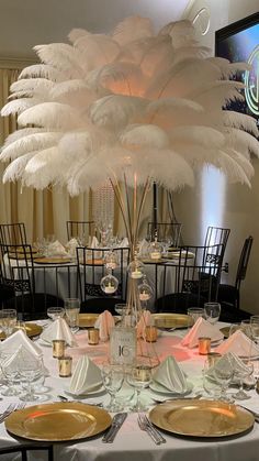 a table set with white and gold plates, silverware and centerpieces in front of a large chandelier