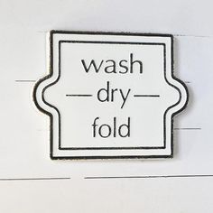 a black and white sign that says wash dry fold on the side of a wall