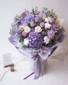 a bouquet of purple and white flowers on a table next to a sign that says, i love you