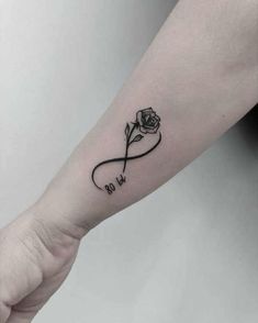 a black and white rose tattoo on the left inner arm, with an inscription that says go to heaven