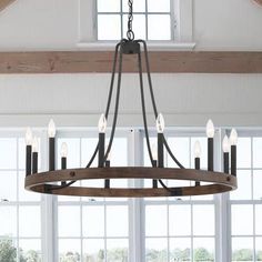 a chandelier hanging from the ceiling in a room with large windows and wooden beams