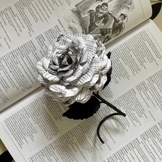 a flower made out of newspaper sitting on top of an open book