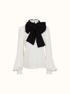 a white blouse with a black bow at the neck and long sleeved top on it