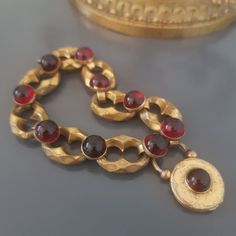 Antique large link bracelet with engraved padlock clasp, gold plated pompom (hallmarked), adorned with round, glass past (garnet imitation) cabochons.  Mid 19th century European work, late Georgian / early Vitorian period.  Dimensions :  Bracelet: L.: 21 cm / 8,2"  Padlock: H: 35 mm, D.: 22 mm  Good antique condition, gilding duller than on photos. To note: gilding wear, missing on one cabochon setting. The clasp works perfectly, originally it was also intended to hold sentimental items, now it cannot be opened. Please take a good look at the photos. I'm happy to combine shipping costs if you buy more than one item. Import duties, taxes, and charges are not included in the item price or shipping cost. These charges are the buyer's responsibility. Please check with your country's customs of Antique Bronze Bracelets For Formal Occasions, Antique Chain Bracelet For Gift, Antique Formal Bracelets With Box Clasp, Antique Gold Bracelets With Cabochon, Antique Gold Cabochon Bracelets, Victorian Gold Bracelets With Cabochon, Ornate Cabochon Bracelet, Luxury Gold Antique-style Charm Bracelet, Vintage Polished Brown Beads, Gems And Cabochons