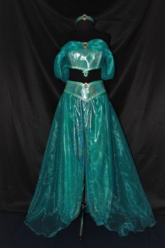 a woman's green costume on display in front of a black backdrop with a blue background