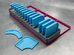 a set of blue and pink plastic objects sitting on top of a metal tray next to each other