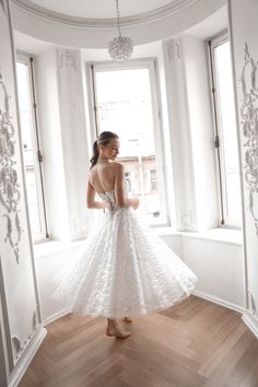 a woman in a white dress is looking out the window