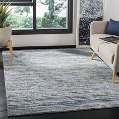 a living room area with a couch, chair and rug in front of a window