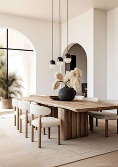 a dining room table with chairs and a vase on top of it in front of a window