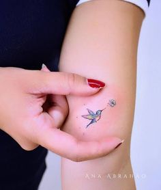 a woman's left hand with a small tattoo on her right arm, and a tiny humming