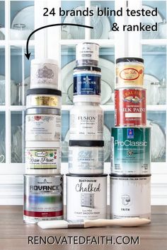 several cans of paint sitting on top of a wooden table next to a white china cabinet