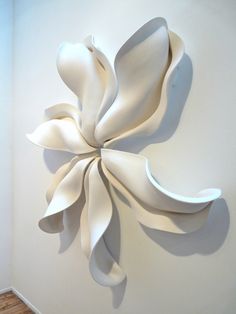 a large white sculpture on the wall next to a wooden floor