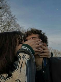 two people kissing each other in front of trees