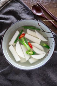 a bowl filled with sliced up celery and other vegetables next to chopsticks