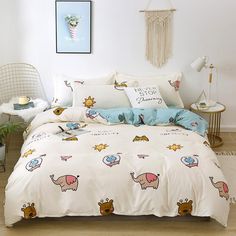 a bed with an elephant and giraffe print on it, next to a chair