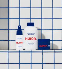 two bottles of hair care sitting on a tiled shelf