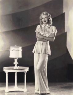 a woman standing in front of a table with a cake on it and her arms crossed