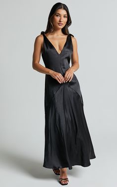 a woman is wearing a black dress with a deep v - neck and side slit