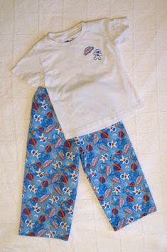 two children's pajamas and t - shirt laying on top of a white bed