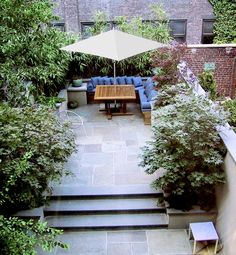 an overhead view of a patio with seating and umbrella in the center, surrounded by greenery