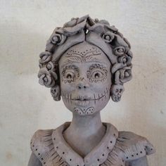 a statue of a woman with flowers on her head and hair in the shape of a skull