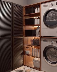 a washer and dryer in a room with wooden shelves on the wall next to each other