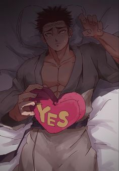 a man laying in bed holding a heart shaped pillow with the word yes written on it