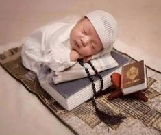 a baby is laying on top of a book and wearing a priest's hat