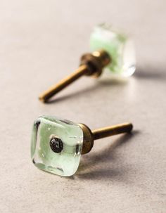 two green glass earrings with gold posts on the top one has a black diamond in it