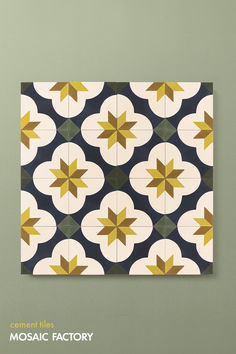 an artistic tile design with yellow and green stars in the center, on a gray wall