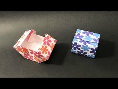 two origami boxes sitting next to each other on top of a black table