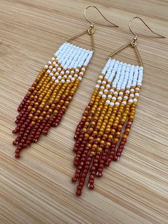 the beaded earrings are made with red, white and yellow beads on wooden surface