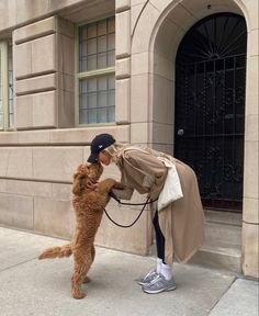 a woman is petting a dog on the side of a building with a coat over it's face