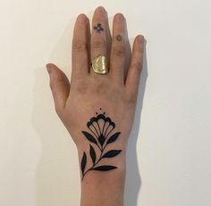 a woman's hand with a tattoo on it and a gold ring in the middle