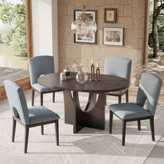 a dining room table with blue chairs and pictures on the wall behind it in front of a window