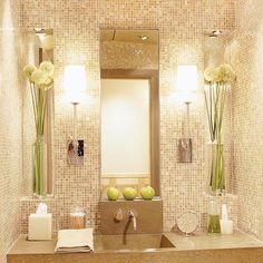 a bathroom sink sitting under a mirror next to two vases with flowers on it