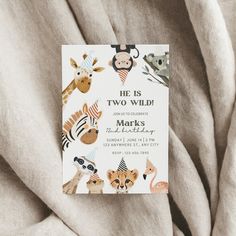 a card with animals on it is laying on a bed sheet that says he is two wild marks