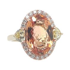 A magnificent 18k Rose and White Gold Natural Imperial Topaz and Diamond Ring. The center stone is a rare peach color natural Imperial Topaz 5.97 carat measuring 13.96x9.44x5.28mm. The center stone is flanked with a matching pair of GIA certified Natural Fancy Yellow heart shapes weighing 0.33 carats (4.3x4.65x2.71mm, VS2 clarity) and 0.31 carats (4.28x4.66x2.65mm, SI1 clarity). Also set are 20 natural round brilliant colorless diamonds weighing 0.30 carats. Total weight of ring is 6 grams, size 5.75… and total gemstone weight is 6.91 carats. Luxury Yellow Topaz Ring Elegant, Luxury Yellow Topaz Ring, Vintage Yellow Topaz Engagement Rings Erstwhile Jewelry, Luxury Yellow Topaz Ring With Polished Finish, Luxury Polished Yellow Topaz Ring, Yellow Rings, Imperial Topaz, Yellow Heart, Colorless Diamond