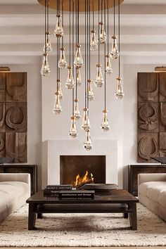 an elegant chandelier hangs over a dining room table with white chairs and vases