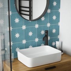 a bathroom sink sitting under a mirror next to a wall mounted faucet in front of a blue and white tiled wall