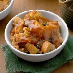 two white bowls filled with food on top of a wooden table next to a green napkin