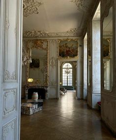 an ornately decorated hallway with mirrors and paintings on the walls is pictured in this image