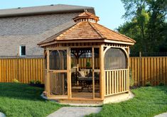 a wooden gazebo sitting on top of a lush green field