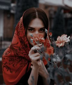 a woman wearing a red scarf holding flowers