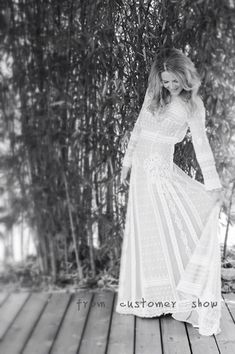 a woman in a white dress standing on a wooden deck