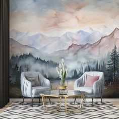 two chairs and a coffee table in front of a wall with mountains painted on it