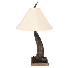 a lamp that is sitting on top of a wooden base with a white shade over it