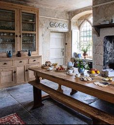 a dining room table with plates and bowls on it in front of a fire place