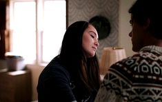 a man and woman sitting on a couch talking to each other in the living room