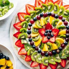 a fruit pizza with kiwis, strawberries, and blueberries on it